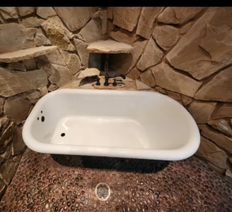 a clawfoot tub refinished in white with a stone wall in tyler texas