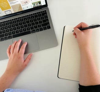 a person's hand is holding a pen and writing on a notebook