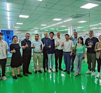 a group of people standing in a factory with thumbs up
