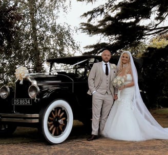 Wedding couple standin by posh car