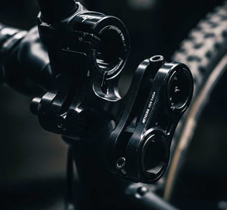A close-up, darkly lit photograph of specialized bike mounts, crafted from dark, possibly anodized metal. The focus is on the
