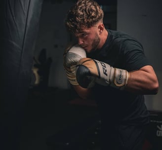 Antrenor echipat cu mănuși de box RDX, în poziție de gardă, pregătit pentru un antrenament intens