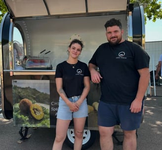 a man and woman standing in front of a food "Chez Tosca" truck