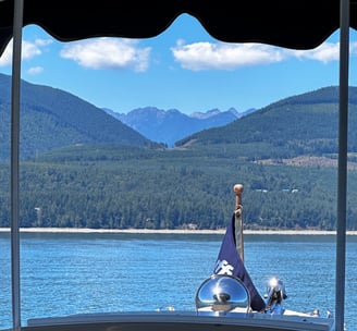 front of boat with flag on pristine water facing majestic mountains