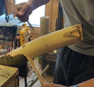 a man is stripping the bark off a log in a workshop 
