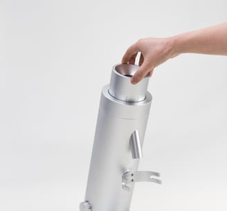 a person's hand holding a silver coffee grinder