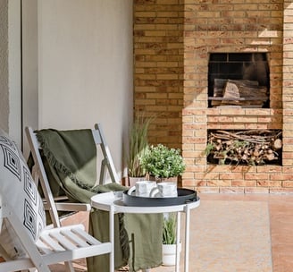 a patio with a table and chairs and a fireplace