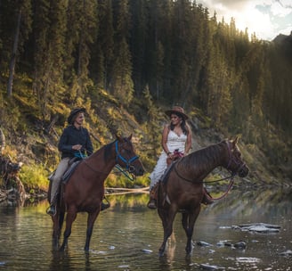 two people riding horses in the water in Banff