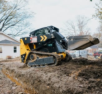 Miniexcavadora realizando trabajos de excavación y traslado de materiales para una obra.