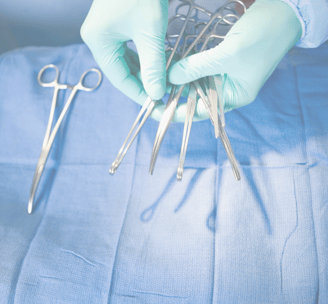 a doctor in a blue gloved hand holding surgical tools