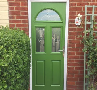 a bespoke bright green front door with diamond lead glass.  there are three windows on the door 
