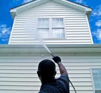 Pressure washing services worker soft washing a vinyl siding house