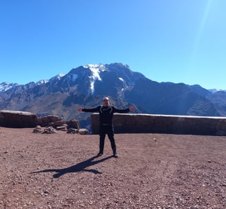 a man standing on a mountain top with his arms outstretched out