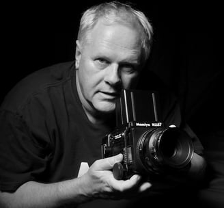 Peter Pickering, photographer, holding a Mamiya medium format camera and taking a picture