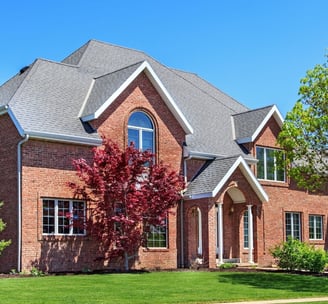 A stately brick house with lush landscaping 