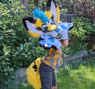 A yellow coyote fursuit featuring a full jaw set of silicone teeth and big ears as well as glow in the dark parts From Teto