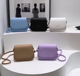 Una exhibición de cinco carteras hermosas en blanco, negro, celeste, morado y marrón