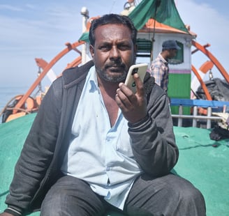 a man sitting on a boat with a cell phone