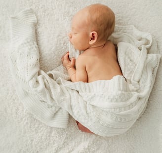 a newborn baby is sleeping in a blanket - Lincolnshire photography studio