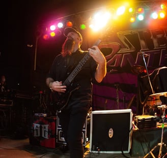 a man playing a 7 string guitar in a band with an EVH amp and a Line 6 Helix