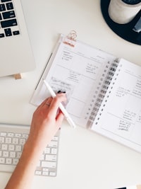 a person holding a pen and writing on a notebook