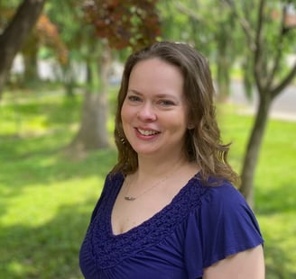 Happy woman facing forward with trees behind her