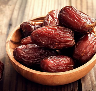 a bowl of dates in a wooden bowl