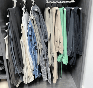 Closet section with pants neatly hung on space-saving cascading hangers.