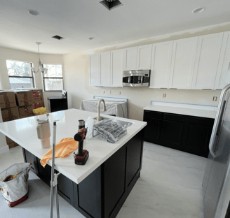 Kitchen setup in progress with tools, moving boxes, and unpacked supplies on the island.