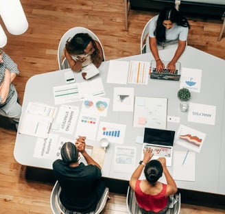 Equipo de marketing reunido alrededor de una mesa analizando gráficos y datos estratégicos para camp