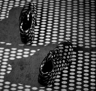 a pair of shoes on a surface with black and white shadows
