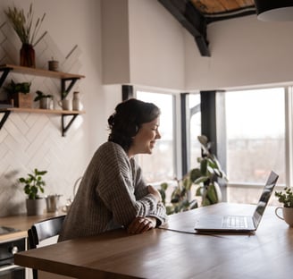 Happy woman video chatting on laptop in kitchen