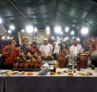 a group of people standing around a table with local food