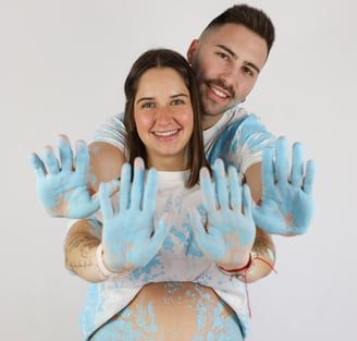 Sessió de fotos de gender reveal a Girona d'una parella amb pintura blava en estudi fotogràfic