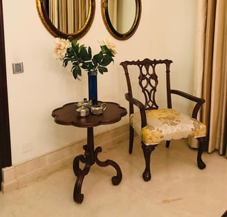 a wooden chair and a wooden table with a vase with flowers