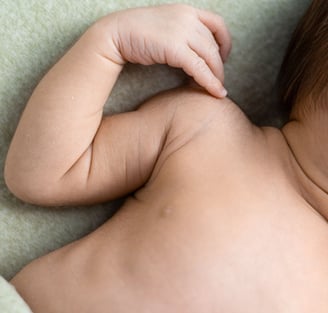 Detall de mans i cos d'un bebè nounat en una sessió de fotos newborn a Girona en estudi fotogràfic