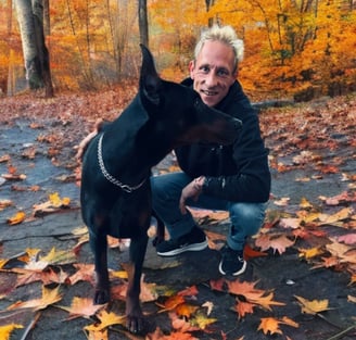 a man with blonde hair and a dog in a park