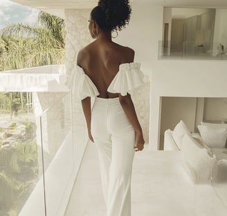 A black woman wearing white with her back to the audience 