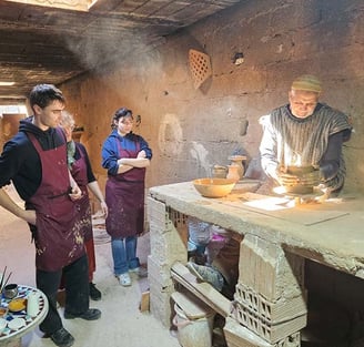 Un artisan devant un tour de poterie en train de créer une coupe en argile