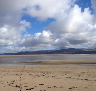 Sand at the dyfi estuary looking at the river Leri channel and hills in the distance