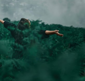 a woman standing in a field with her arms outstretched out
