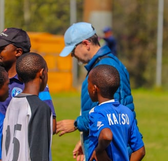 a man in a blue shirt is talking to a group of young boys