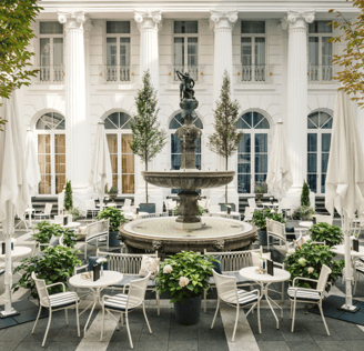 Ein Springbrunnen in einem Innenhof mit weißen Stühlen und Tischen.