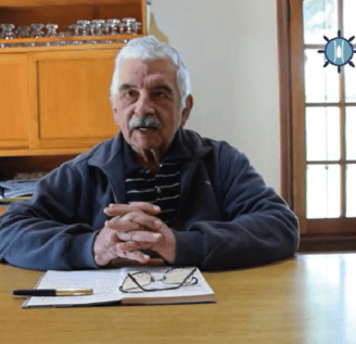 el capitan longa sentado y apoyado en una mesa