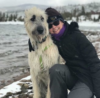 The author hugging her Irish Wolfhound by a snowy mountain lake