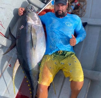  A man in a blue shirt is holding a huge yellowfin tuna on a Zanzibar fishing charter