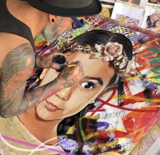 Sérgio Astral em seu estúdio, trabalhando em uma pintura à mão com tinta acrílica e spray.