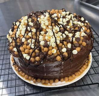 Chocolate cake with caramel, chocolate, and white chips, and drizzled with caramel and chocolate.