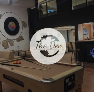 Interior de The Den Cannabis Club con mesa de billar y logotipo