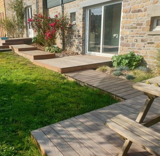  Terrasse en bois composite avec accès en pas japonais, installée le long d'une maison en pierre